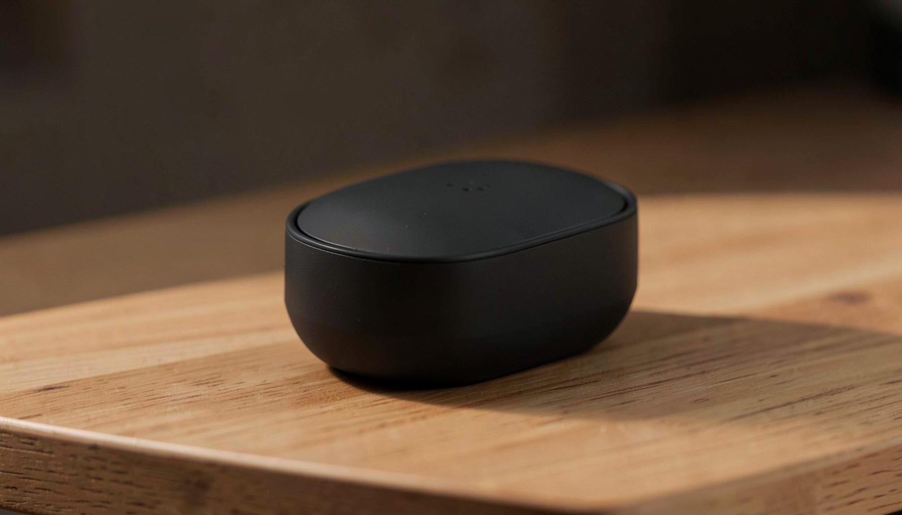 A compact pod-style device resting on a minimalist wooden surface, bathed in warm ambient light with subtle shadows